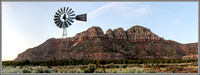 Panoramic photo of a western ranch windmill with a Southwest butte in the background.